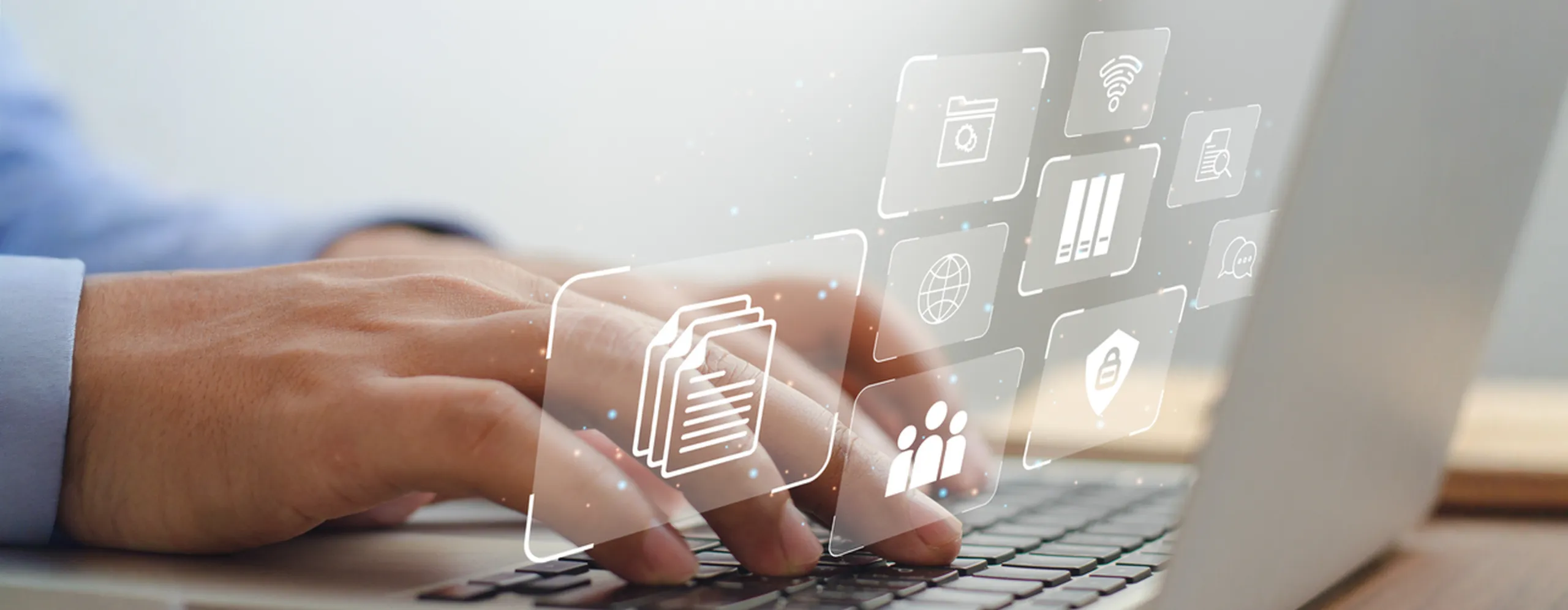 hands typing on a laptop with digital file and security icons floating above the keyboard, representing how open it’s software license management tools help streamline asset tracking and access control.